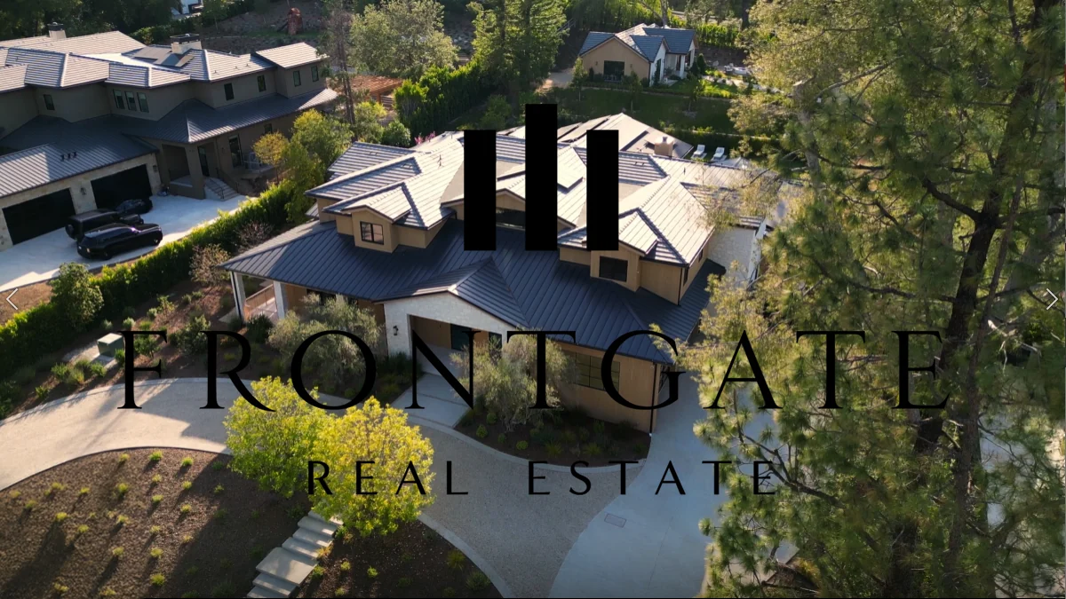 Aerial view of a large modern hillside home and its driveway, with Frontgate Real Estate title text