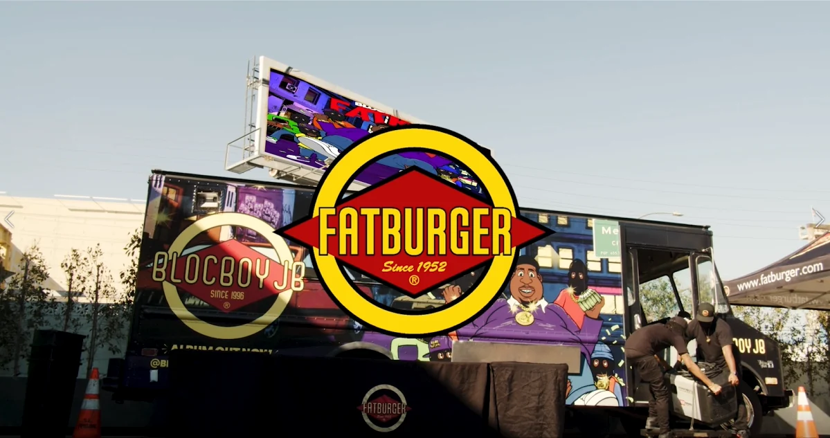 Fatburger and BlocBoy JB logos over a branded truck at an outdoor event, with crew setting up beside it